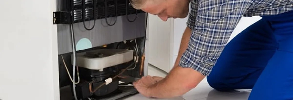 Refrigerator repair technician servicing the compressor and condenser area in Allentown, PA