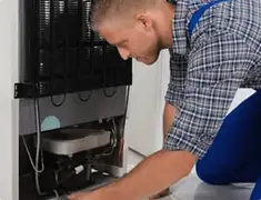 Refrigerator repair technician servicing the compressor and condenser area in Allentown, PA