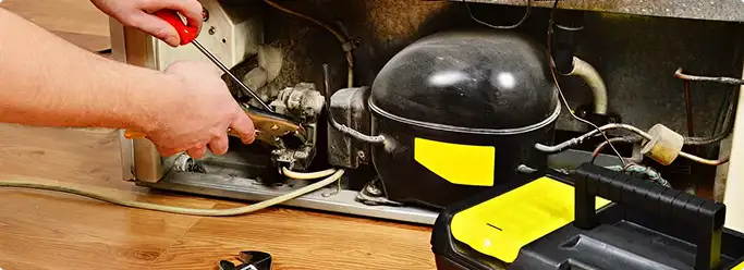 Refrigerator repair technician fixing the compressor and wiring in Allentown, PA